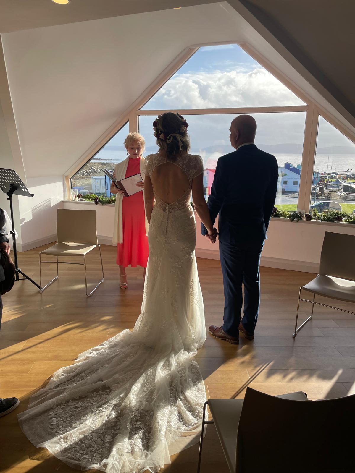 Couple at the altar during their wedding ceremony with Edel Garvey, sea light flooding the room