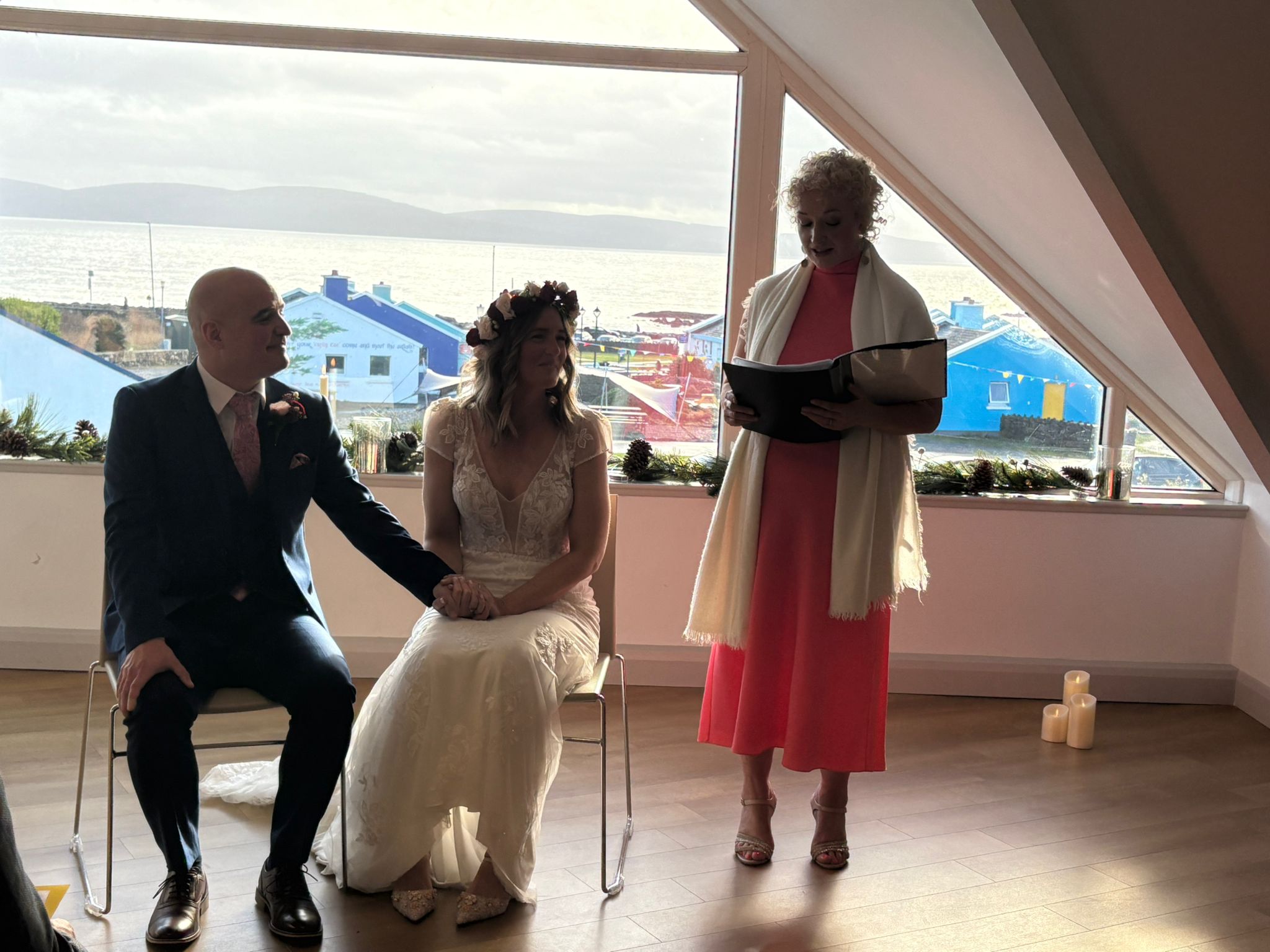Edel Garvey conducting a wedding ceremony with the Atlantic coast visible through the window