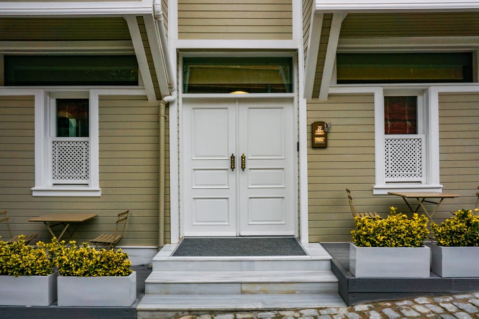 A welcoming home entrance with double doors and flowering planters on either side