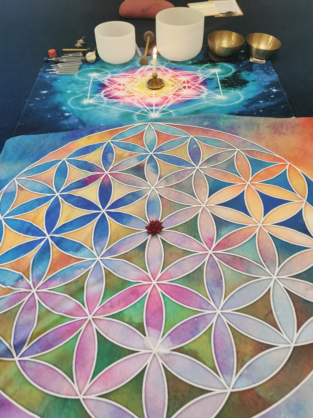 Flower of Life mandala cloth with a single red rose at its centre — detail from Edel's sound healing space