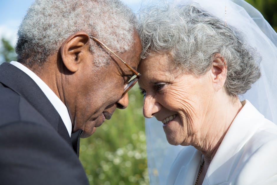 Senior couple in wedding attire touching foreheads and smiling during a vow renewal